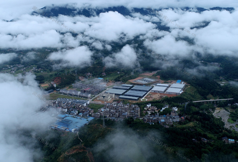 2024年5月26日，雨后的湖南省桂东县大塘镇，罗霄山脉下，一排排一幢幢新建的工业厂房与大塘集镇隔106国道相望，漂动的流云给大塘镇覆上了一层神秘的面纱，一座新兴的工业小镇如梦似幻。