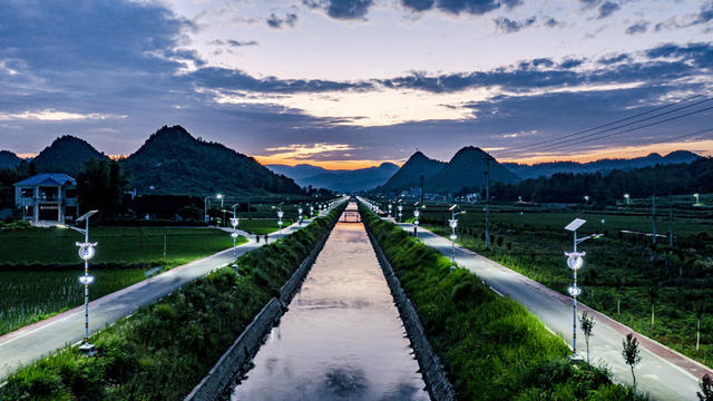 
近年来，湘西花垣县龙潭镇双坪村基础设施建设项目在省发改委驻村工作组的督导下有序进行中。

“项目总投资及资金500万元，资金来源为中央预算内以工代赈资金。
建设内容及规模为改扩建村部文化广场4200平方米、产业道路(宽6.5米)1250米、双坪村道路改造(宽3.5
米)2780米、步行道改造2520米、排洪工程1100米以及管道灌溉工程1800米等工程建设。另还修建1152平方米鸡枞菌种植基地1个，1530平方米养蚕产业基地1个，900平方米笼养鸡屠宰场1个等产业工程，目前还计划利用原选矿厂覆土三百多亩的尾矿库兴建一座中型光伏发电站，发展多条集体产业，提高村民就业率和村集体经济收入。
项目建设使龙潭镇产业基础设施更加完善，服务设施和体系更加健全，巩固脱贫攻坚成果，防止返
贫致贫。同时通过以工代赈方式，带动当地群众务工人数124人，预计发放劳务报酬154.71万元，占总投资30.94%，就业技能培训务工群众78人，直接增加当地群众收入，提高群众务工技能，促进当地群众家门口就业增收，克服“等靠要”思想，进一步增强他们依靠自身劳动实现增收致富的信心和决心，调动广大农民参与乡村振兴战略实施的积极性、主动性，激发群众内生动力，实现扶志扶智结合，为全县和湖南省在今后以工代赈政策实施中起到良好的示范带动作用。