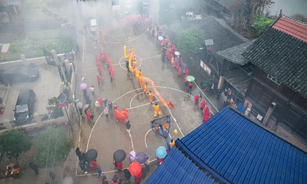  舞龙 传统文化 民俗表演 节日庆典 中国风 古镇 丰收 祈福 热闹 喜庆 民间艺术 雨天 龙 表演 文化传承 红色 队伍 篮球场 航拍 户外 
