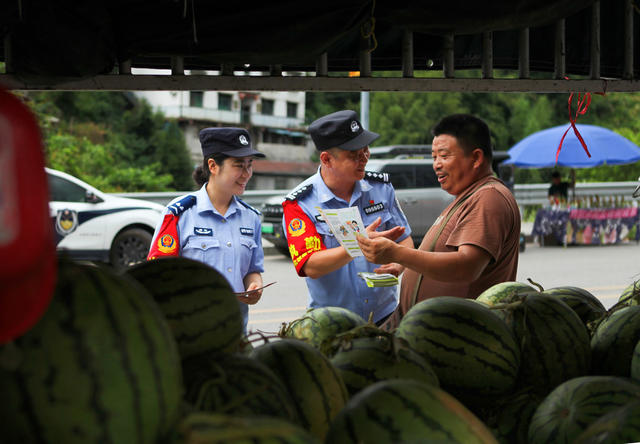 民警对路边瓜摊群众进行反诈宣传